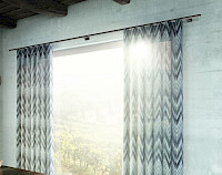 Die edle Vorhangstange mit Innenlauf unterstreicht den modernen Charakter des Stoffes und gibt dem Fenster einen schönen Rahmen. (Foto: interstil)
